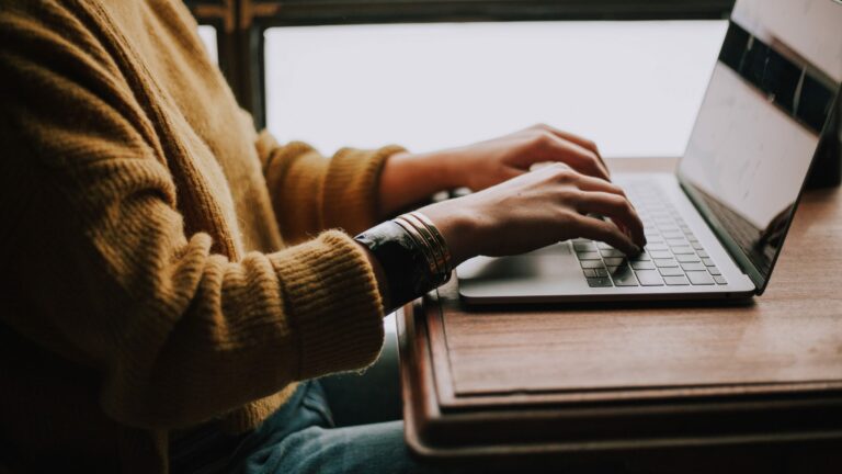 close up of hands working on laptop