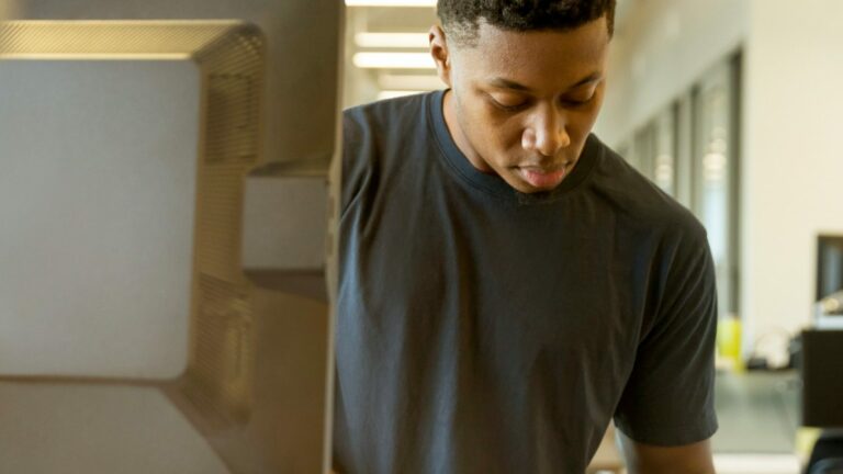 young man standing at desk writing on notepad