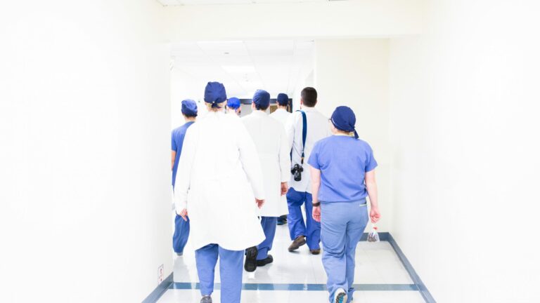 view of back of group of medical professionals walking down corridor