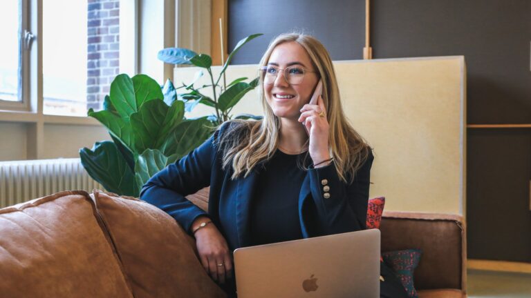 Smiling woman sitting on sofa using a mobile phone