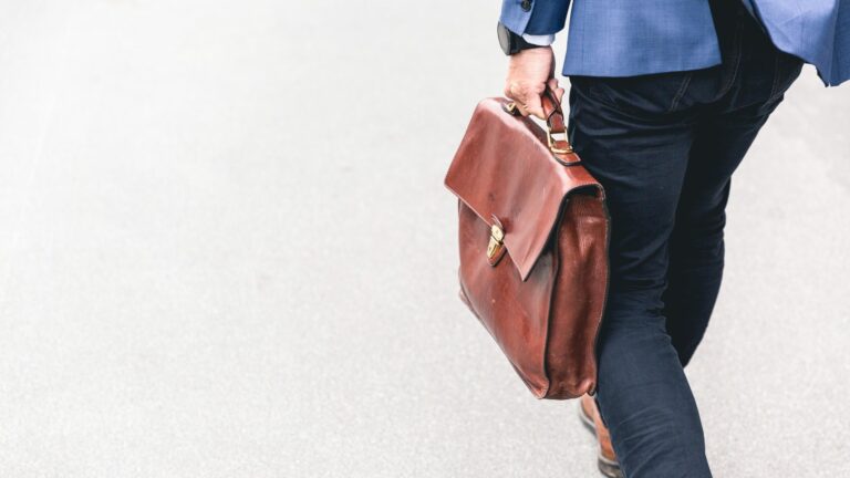 man walking carrying briefcase see from behind