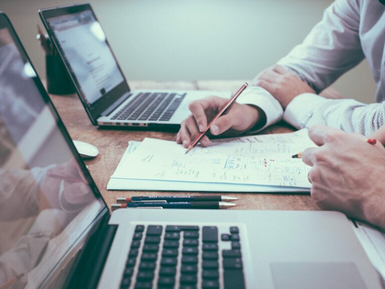 2 people with laptops working on paper document