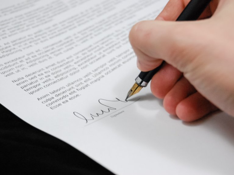 alt=“Person signing document”
